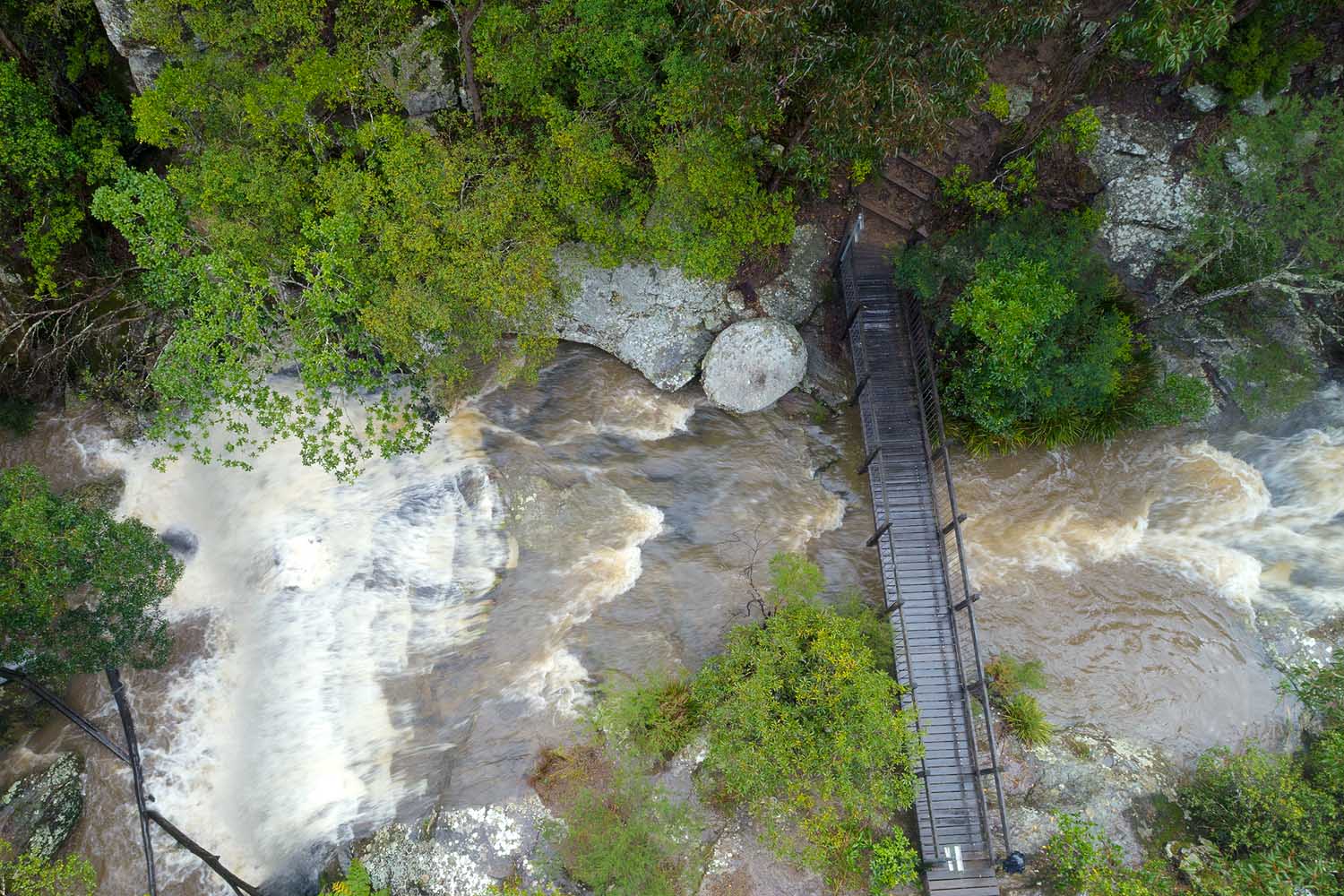 Waterfall flowing through Glenrock State Conservation Area along the Yuelarbah Walking Track, surrounded by native bushland and rainforest vegetation.
