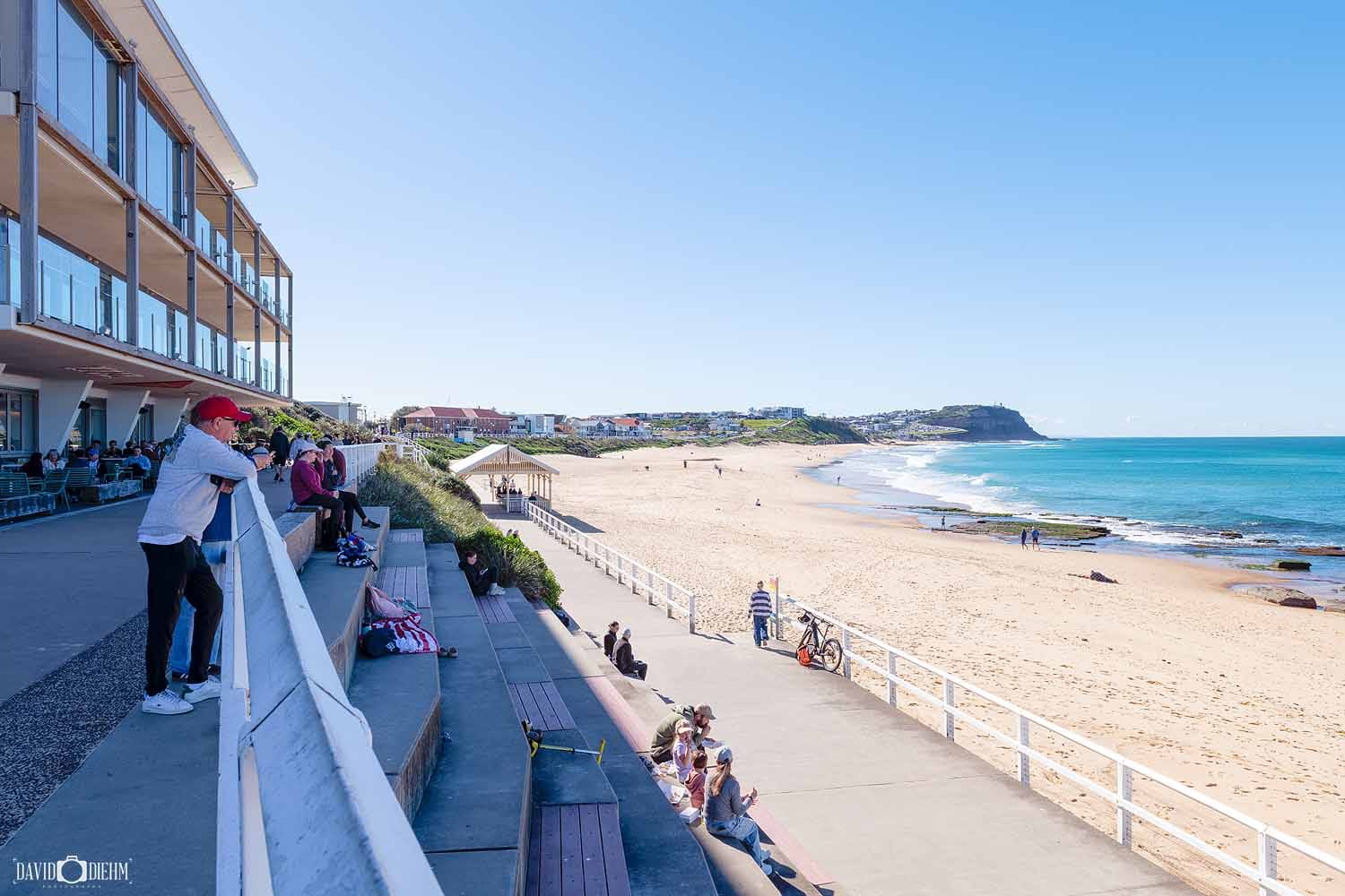 People enjoying the Bathers Way Coastal Walk overlooking Merewether Beach in Newcastle NSW, with the coastline stretching north towards Bar Beach.