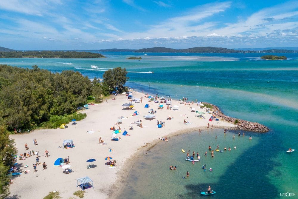 Families swimming and paddleboarding at Naru Beach on the shores of Lake Macquarie