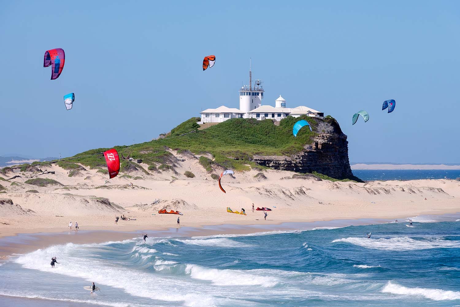 Nobbys Beach and Nobbys Lighthouse with surfers and kitesurfers enjoying Newcastle's coastline in NSW.