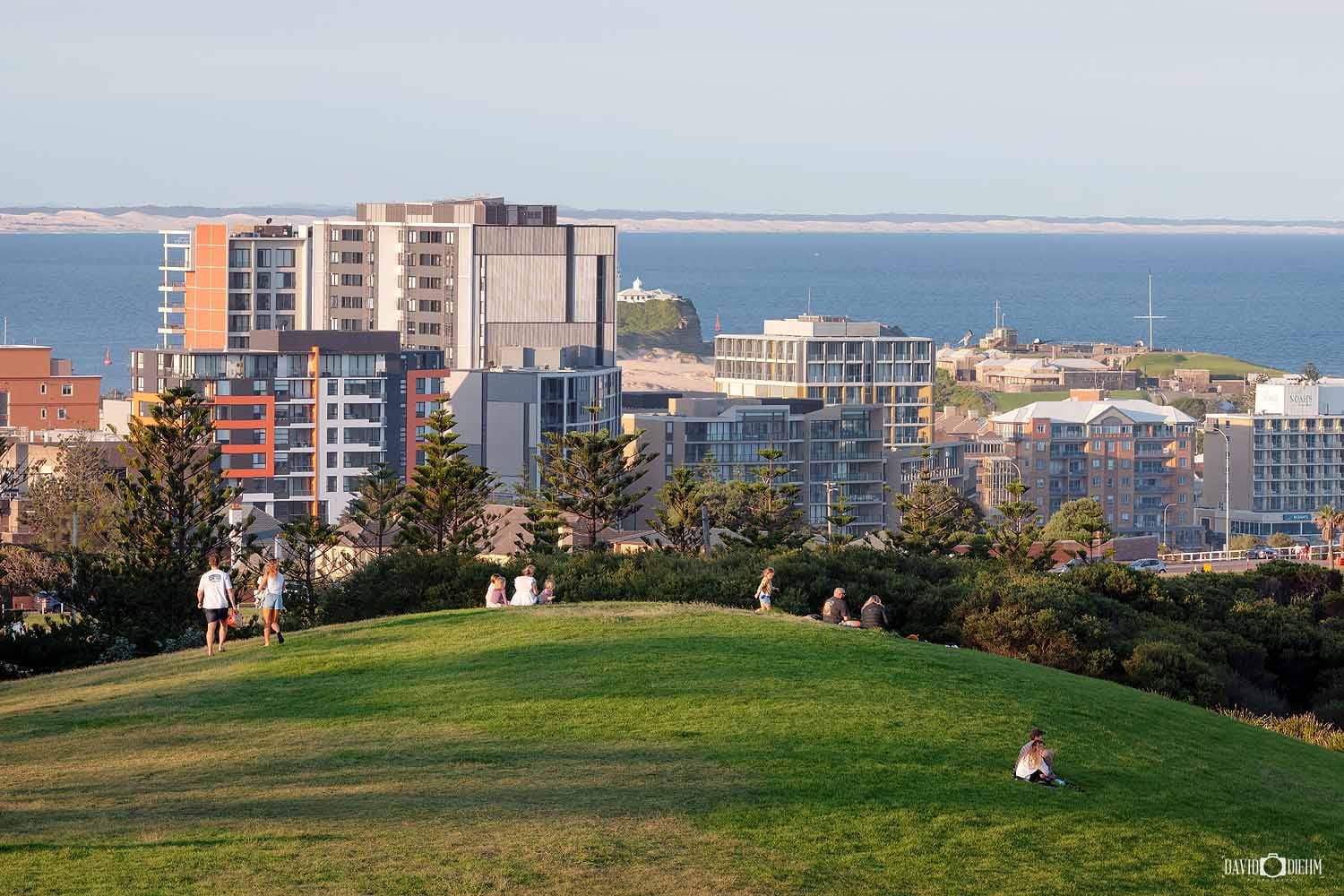 Visitors enjoying the hilltop lookout in King Edward Park overlooking Newcastle city and Nobbys Headland.