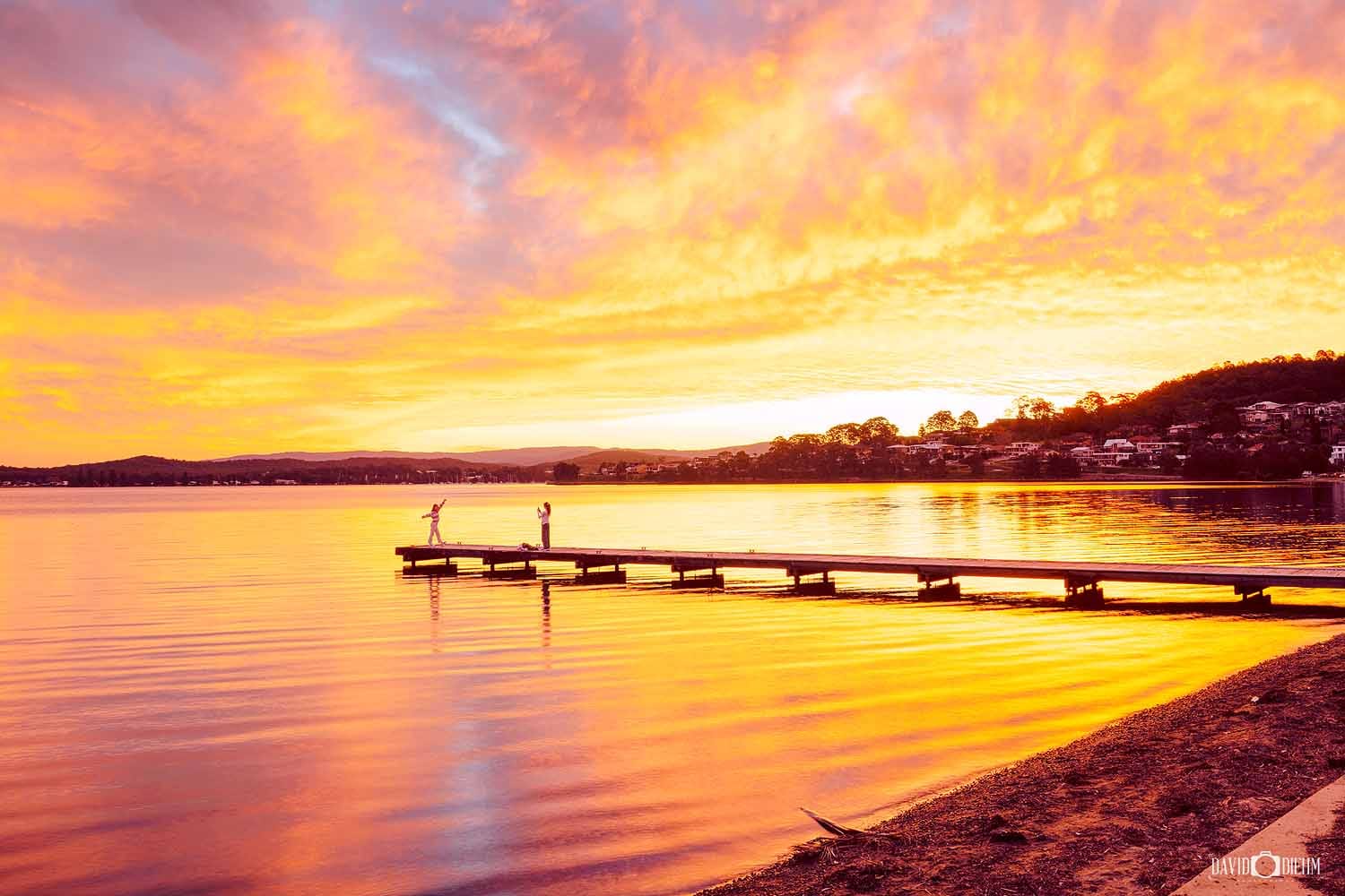 Sunset over Warners Bay Jetty on Lake Macquarie with colourful reflections across calm water.