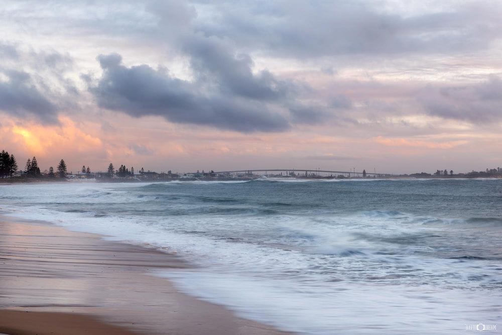 stockton-beach-stockton-bridge-newcastle.jpg Waves rolling onto Stockton Beach with Stockton Bridge visible in the distance near Newcastle NSW.