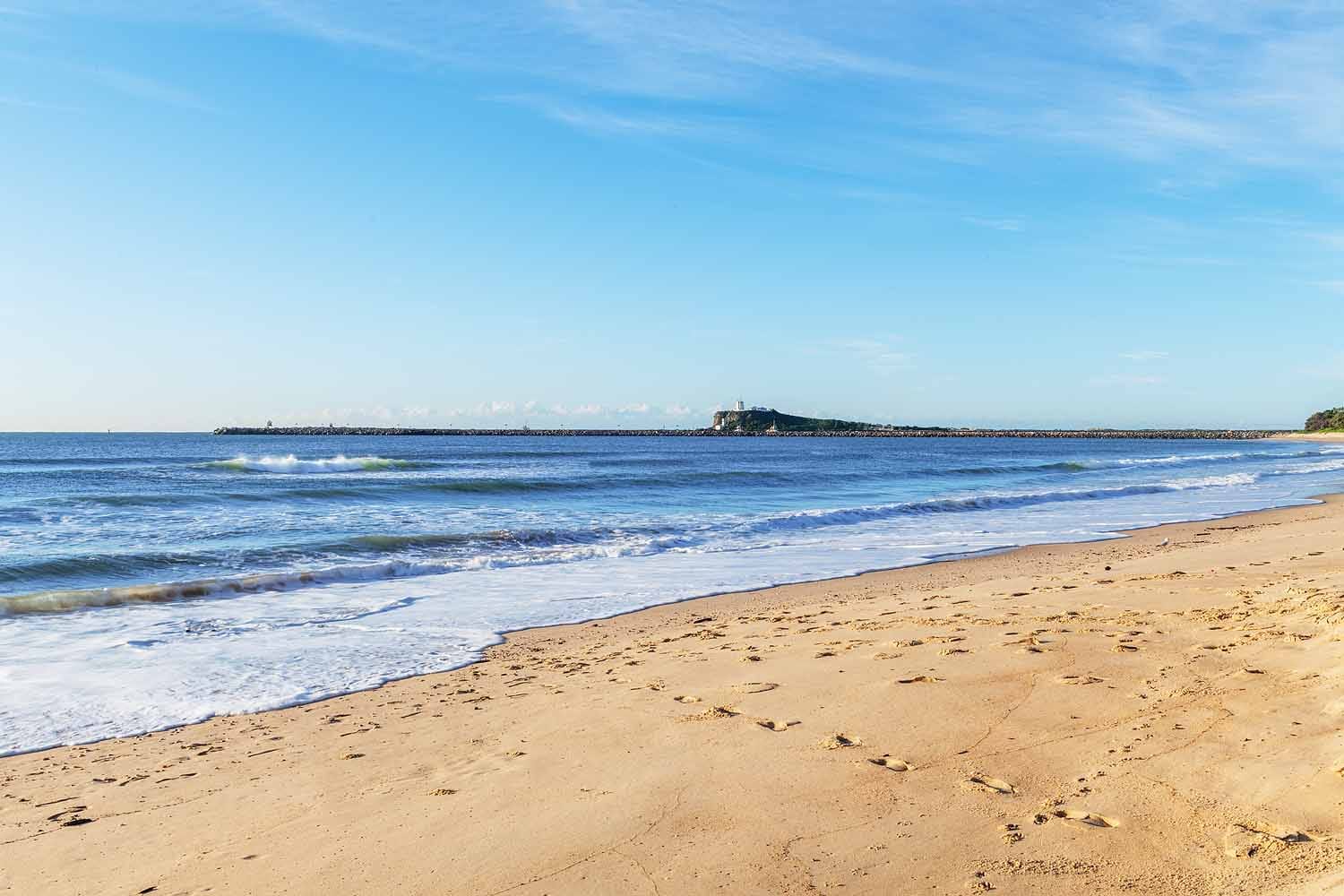 Stockton Beach in Newcastle NSW looking south towards Nobbys Lighthouse and the harbour breakwall.