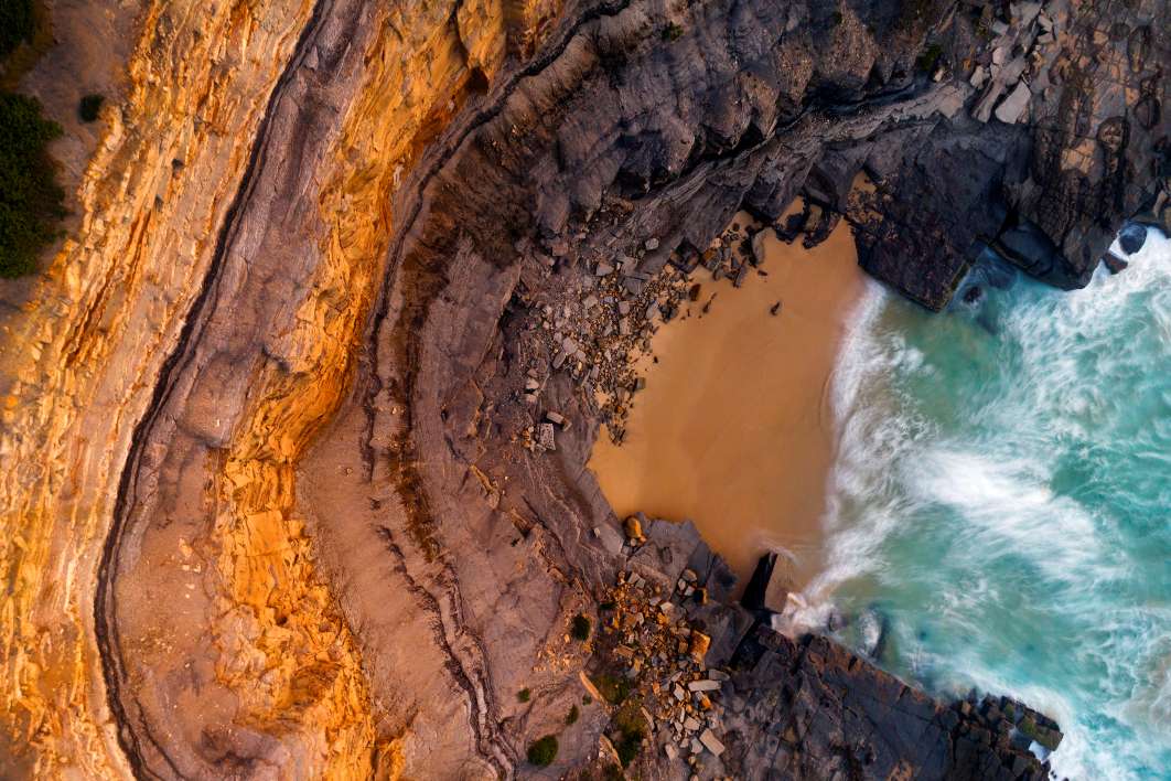 susan-gilmore-beach-aerial-newcastle.jpg Aerial view of Susan Gilmore Beach showing sandstone cliffs, rock platforms and turquoise ocean water in Newcastle NSW.