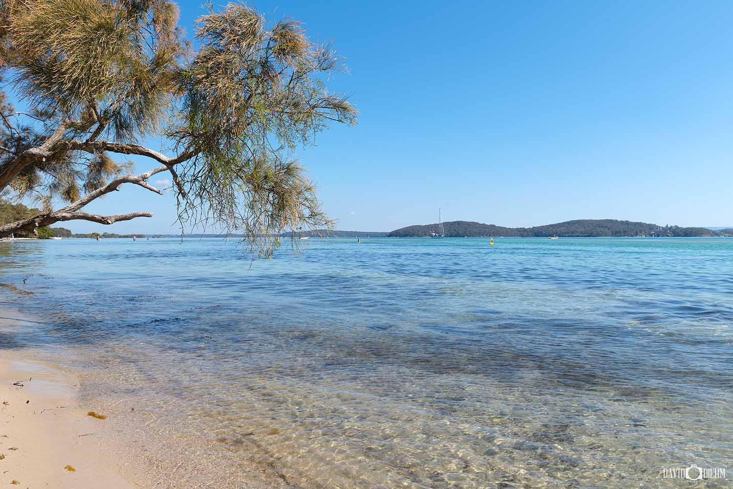 Calm shallow water and sandy shoreline at Swansea Bay Beach in Lake Macquarie.