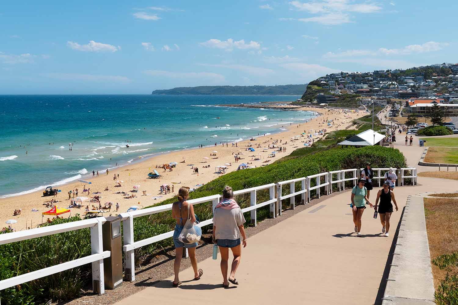 People walking along the Bathers Way Coastal Walk above Bar Beach, with views south towards Merewether Beach, Merewether Ocean Baths and the Newcastle coastline.