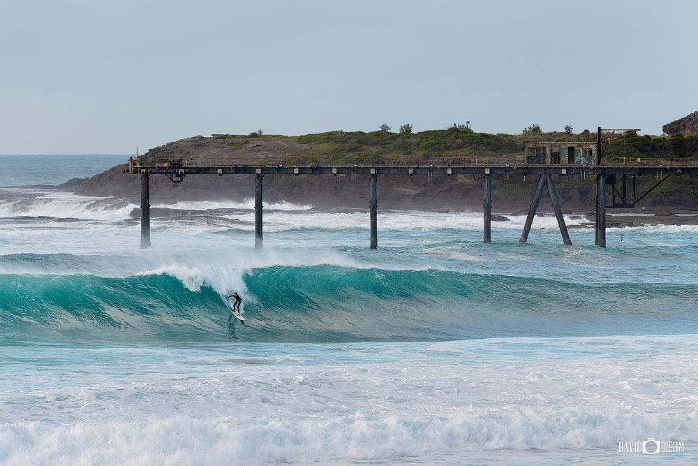 catherine-hill-bay-jetty-surfing.jpg Surfer riding a wave beneath the historic Catherine Hill Bay Jetty in Lake Macquarie NSW.