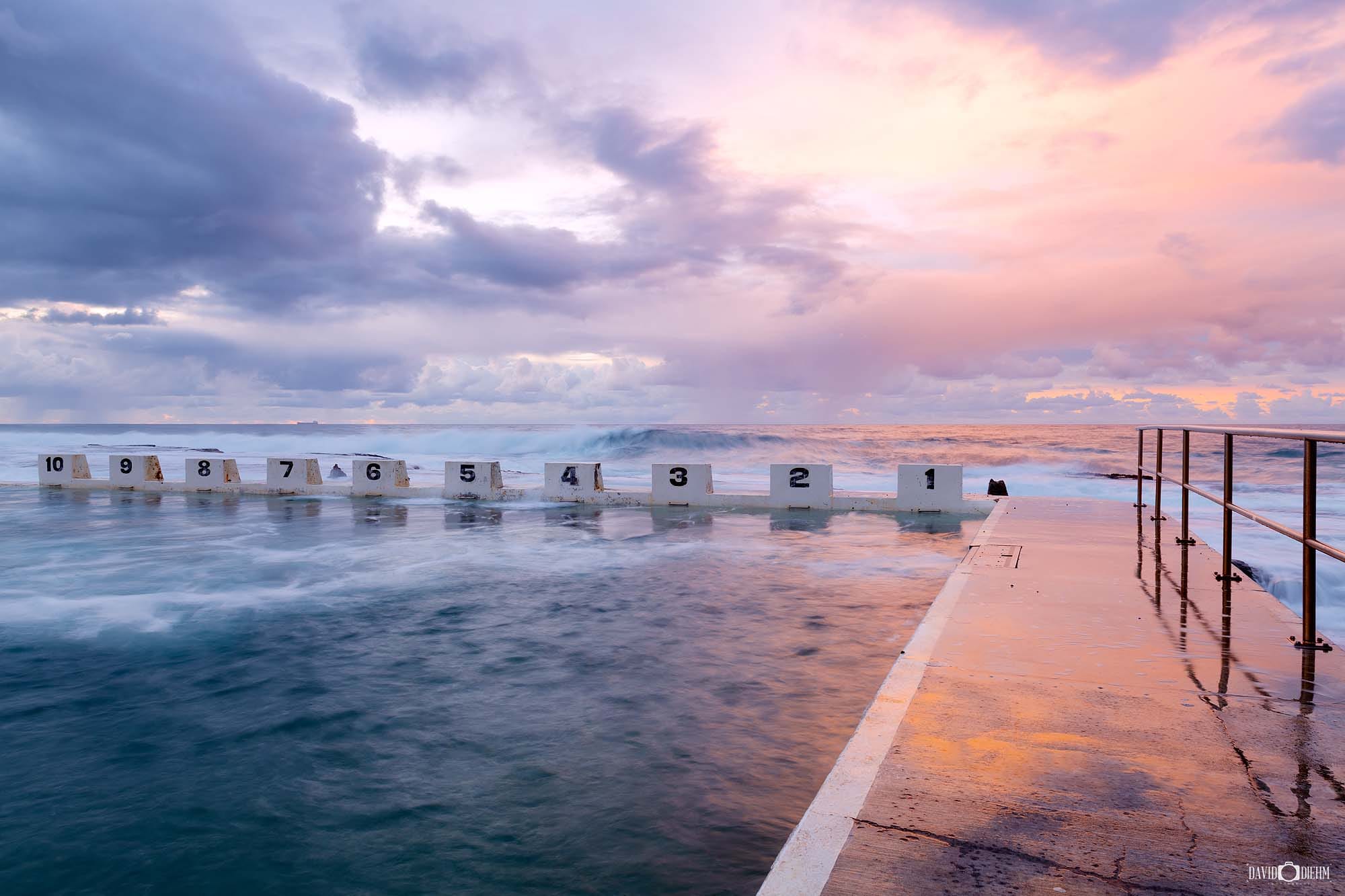 Sunrise over Merewether Ocean Baths with waves rolling into the iconic ocean pool in Newcastle NSW.