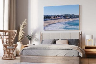 Framed Bondi Beach and Bondi Pavilion wall art displayed above a bed in a modern bedroom.