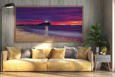 Framed wall art featuring a colourful sunrise over Nobbys Lighthouse with seagulls on Nobbys Beach displayed in a modern living room.