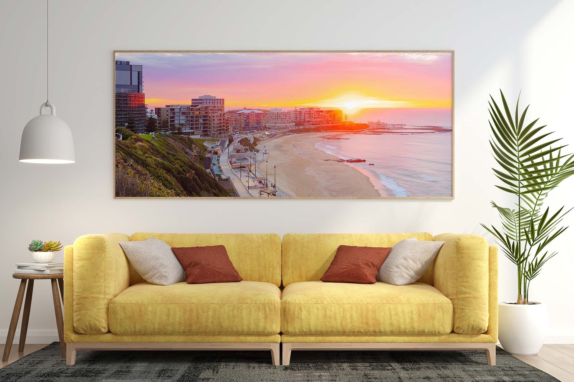 Framed panoramic wall art featuring a sunrise over Newcastle Beach displayed in a modern living room.