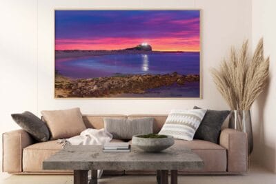 Framed wall art featuring a colourful sunrise over Nobbys Lighthouse displayed in a modern living room.