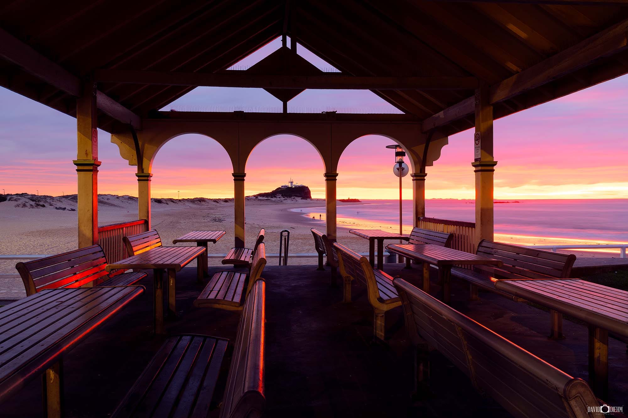 Sunrise viewed through Nobbys Pavilion overlooking Nobbys Beach and Nobbys Lighthouse in Newcastle NSW.