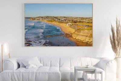 Bar Beach Newcastle aerial photograph displayed as large framed coastal wall art in a modern living room.