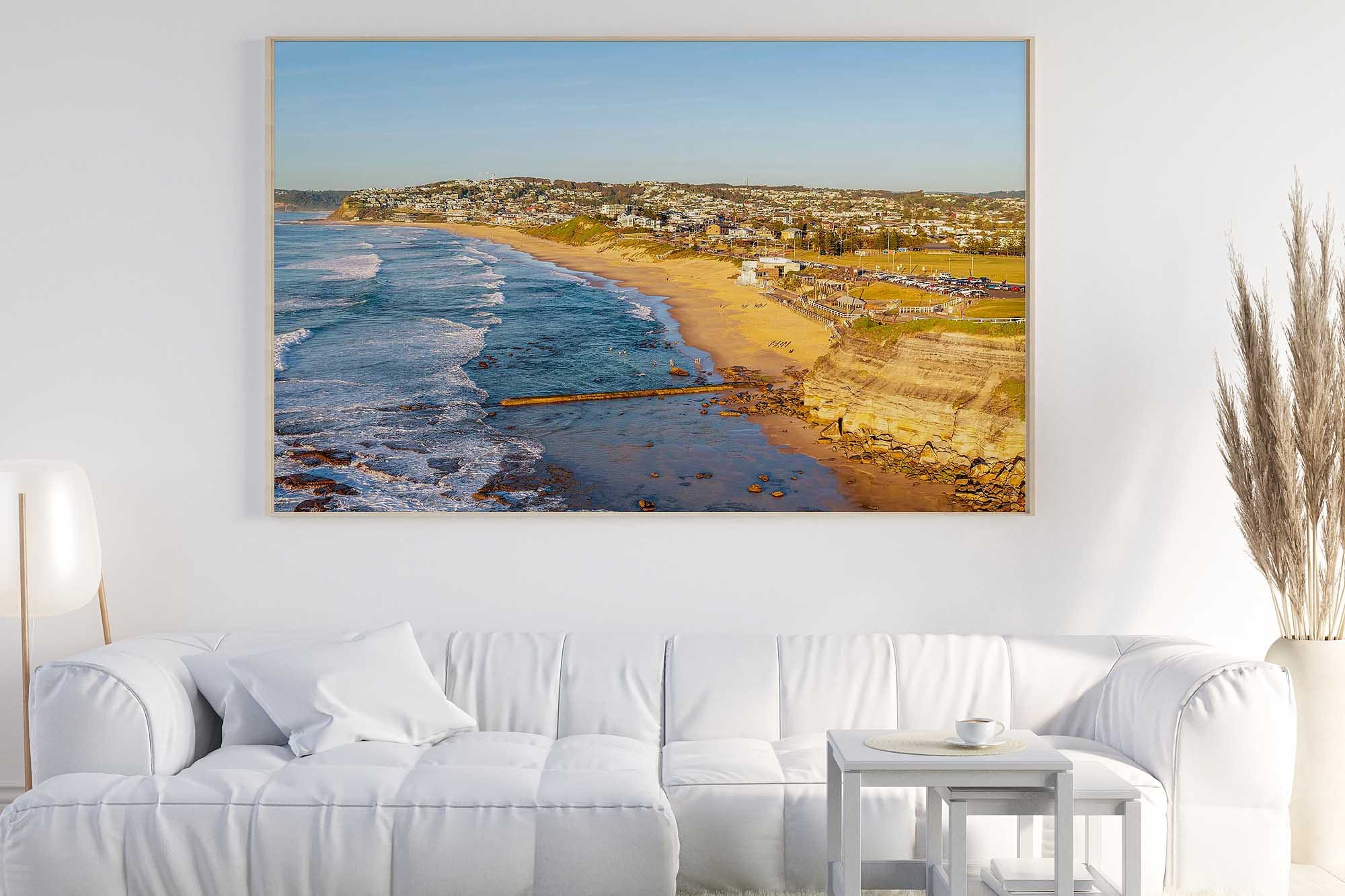 Bar Beach Newcastle aerial photograph displayed as large framed coastal wall art in a modern living room.