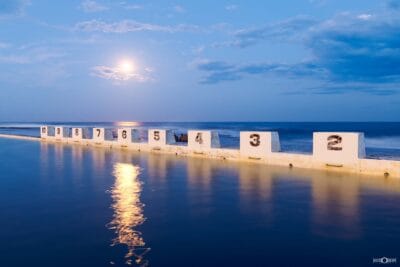 Moonlight reflecting across Merewether Ocean Baths in Newcastle NSW, with the iconic numbered starting blocks overlooking the ocean.