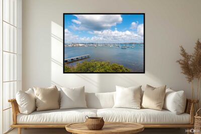 Framed landscape photograph of Belmont Marina, Lake Macquarie, displayed above a lounge in a bright coastal-inspired living room.