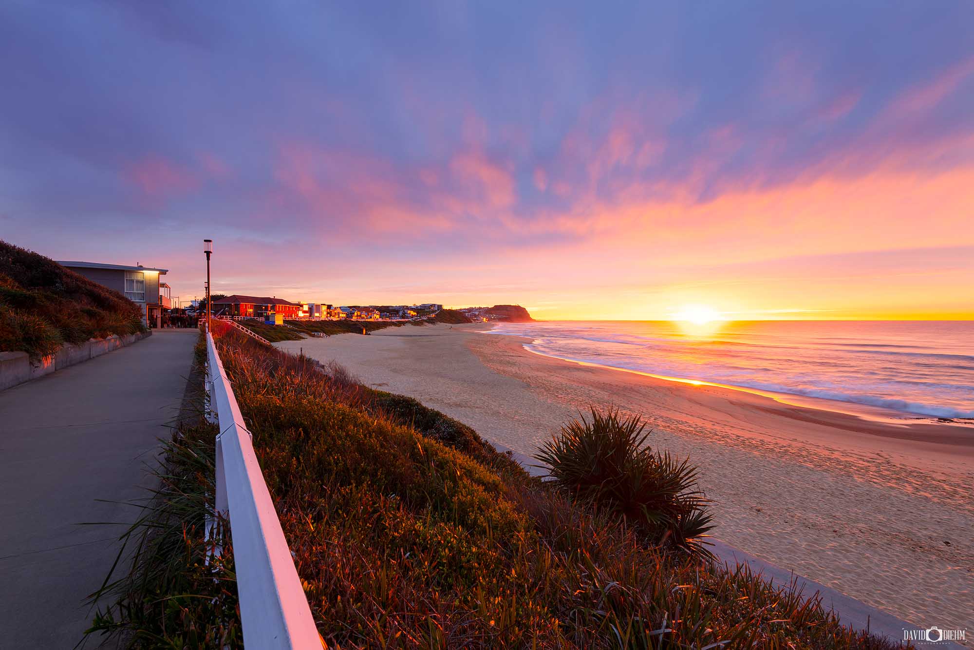 Spectacular sunrise over Merewether Beach, Newcastle, with soft pink, purple and golden clouds illuminating the coastline.