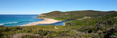 Panoramic landscape photograph of Glenrock State Conservation Area near Newcastle NSW, featuring Glenrock Lagoon, a secluded sandy beach, turquoise ocean and surrounding coastal bushland.