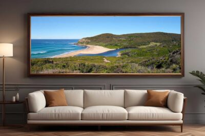 Glenrock Coastal Sanctuary panoramic landscape photography print displayed in a dark timber frame above a cream sofa in an elegant contemporary living room.